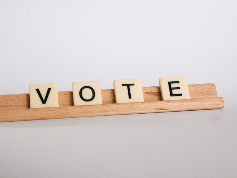 Scrabble tiles spelling out VOTE on a white surface