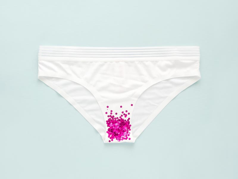 A pair of white underwear with pink glitter on a green background