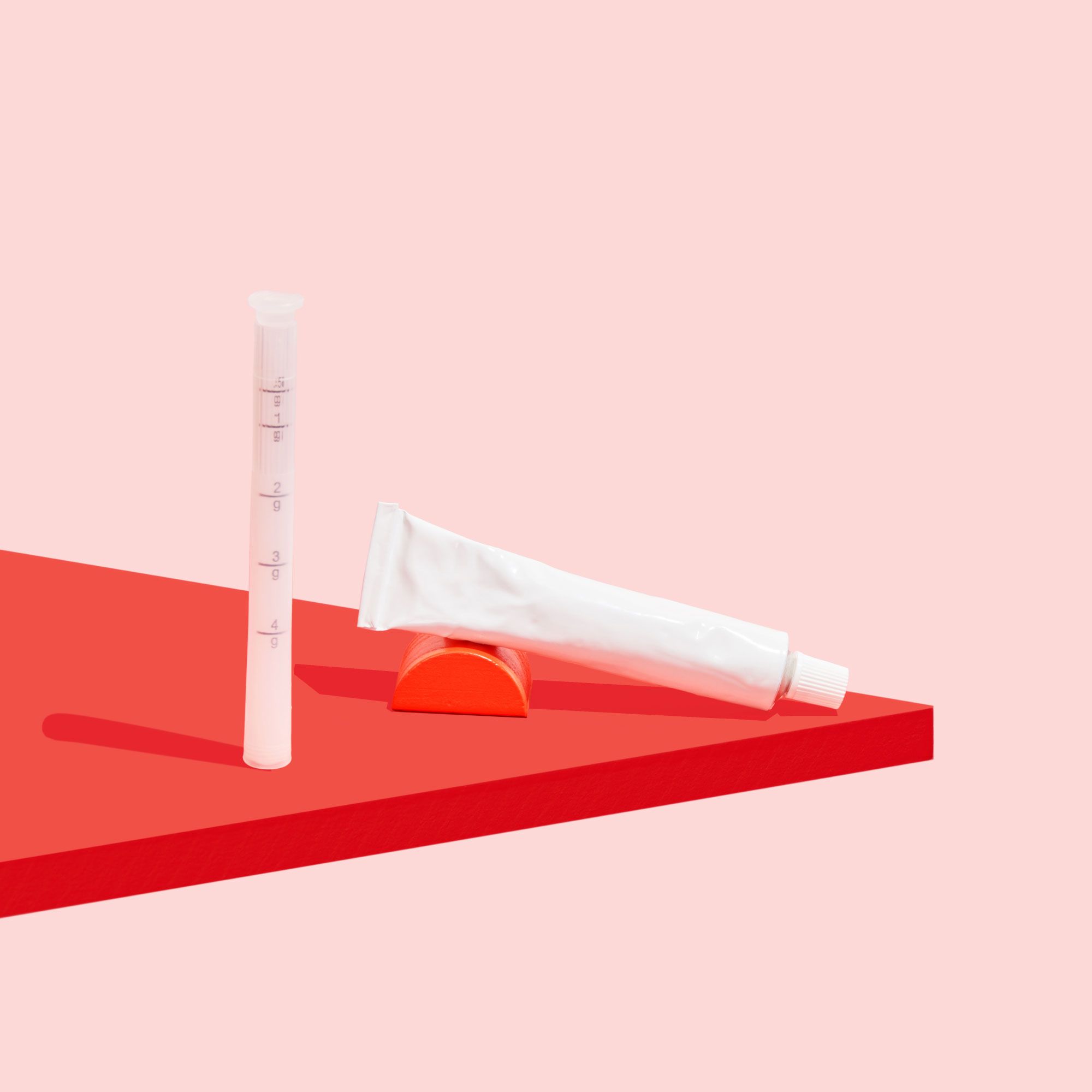 Tube of estradiol cream on a red surface with a pink background