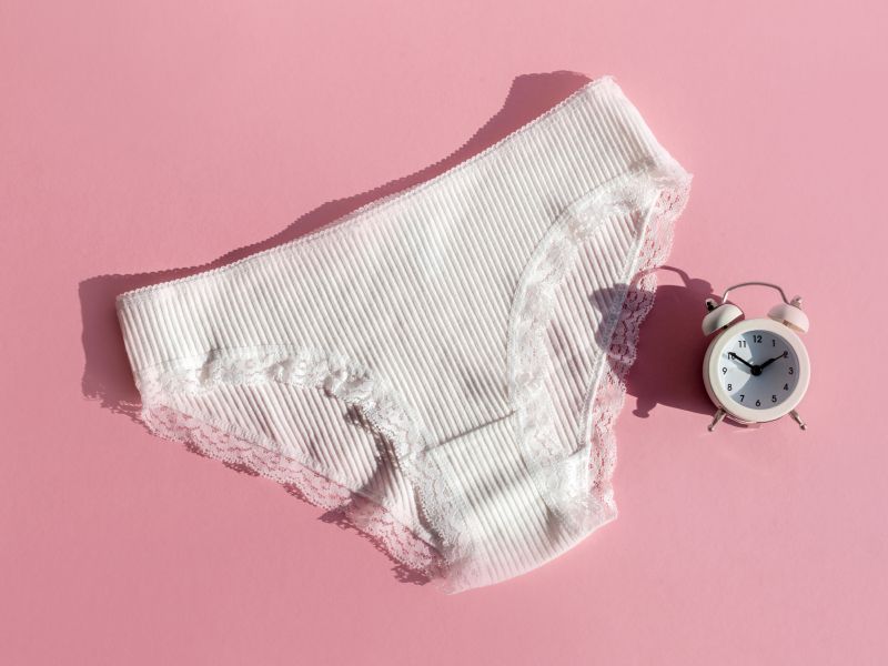 White underwear with a white alarm clock on a pink background
