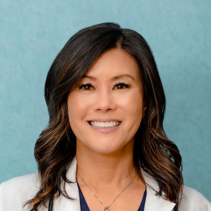 Dr. Rowena Chua, MD wearing a white lab coat in front of a green background