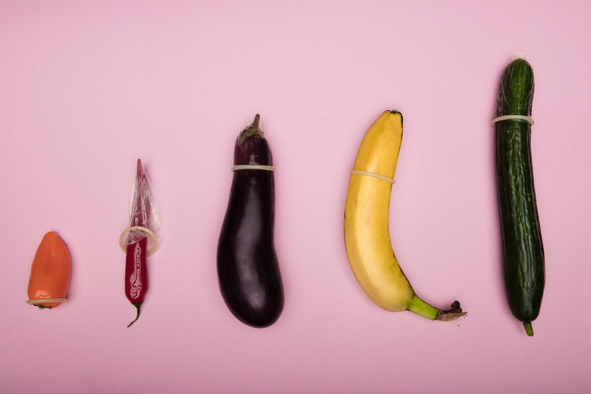 Several different sized vegetables with condoms on them