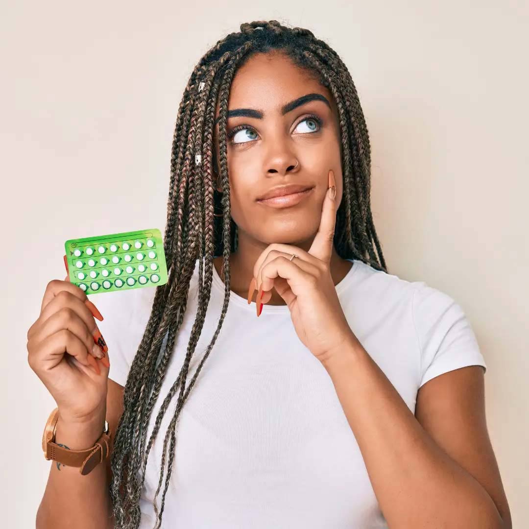 Woman holding birth control packet with a questioning face