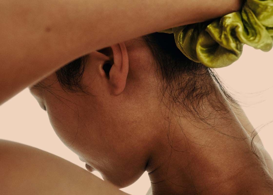 A close up of a woman putting her hair up in a chartreuse scrunchie