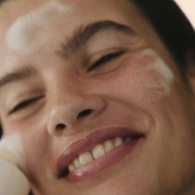 A close up image of a woman's face with cleanser on it