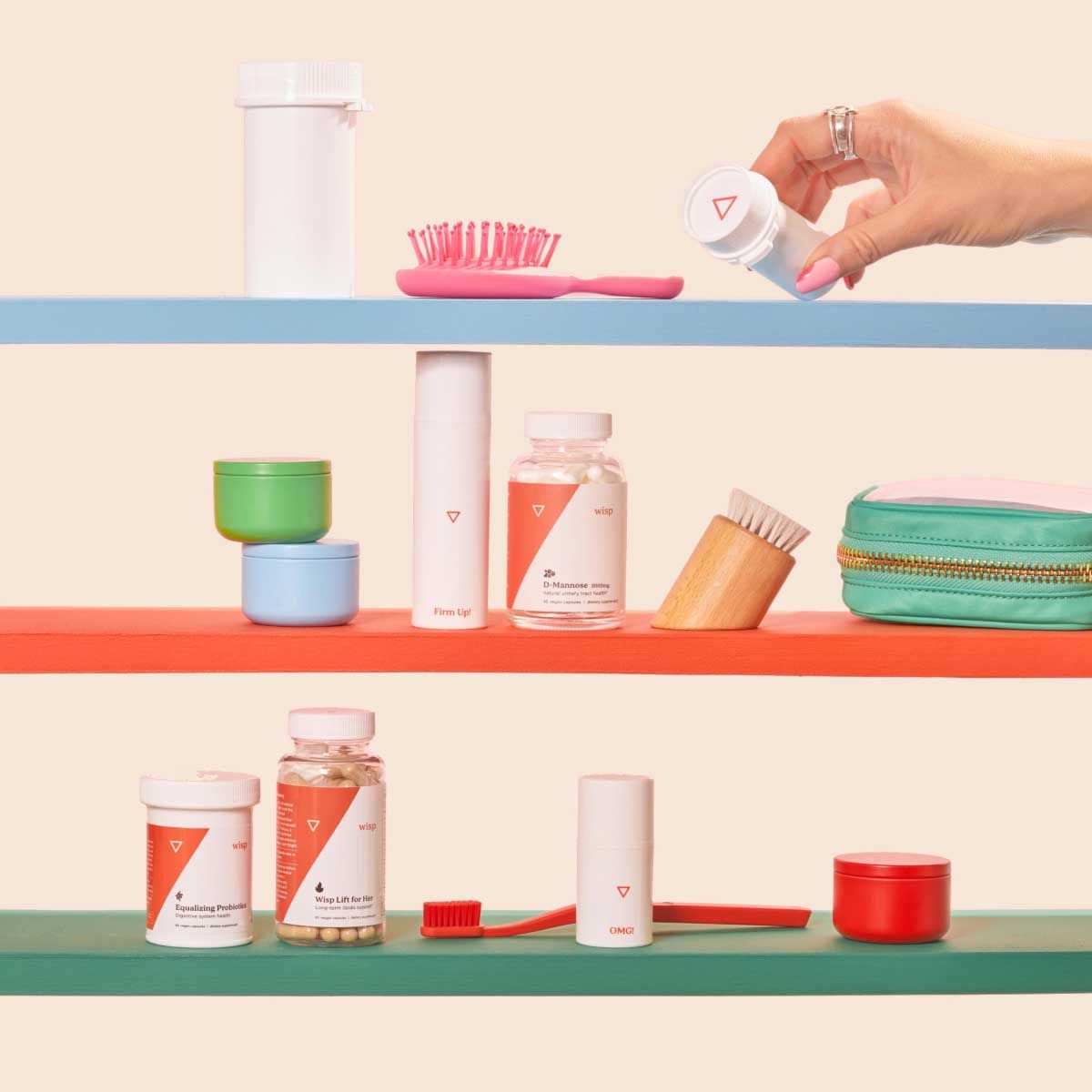 A woman's hand reaching for various Wisp medication bottles balanced on clear abstract shapes on a red surface with a cream background
