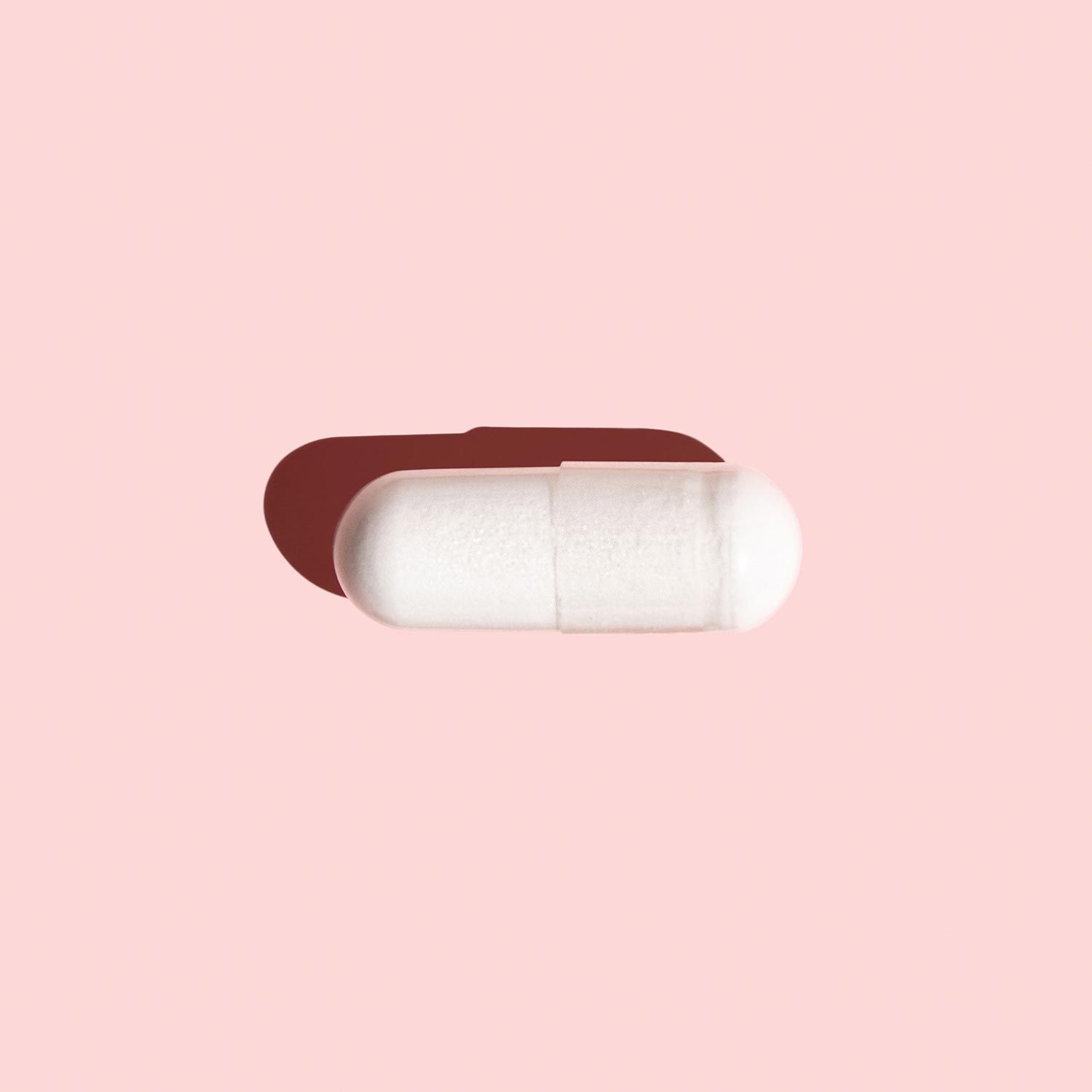 Single boric acid suppository on pink background