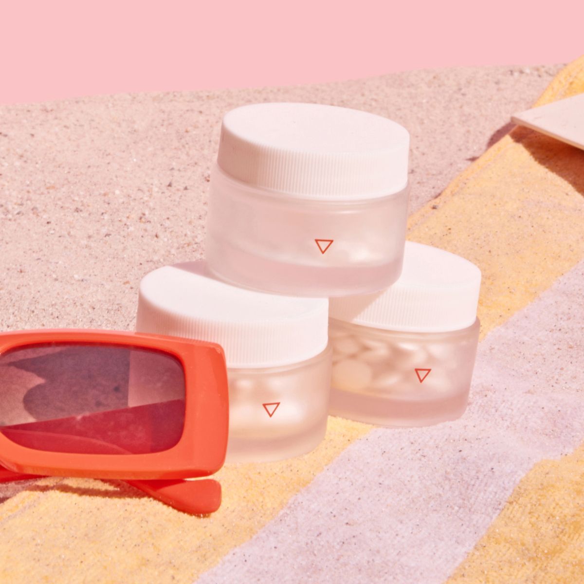 Three small jars stacked on top of beach towel and sand
