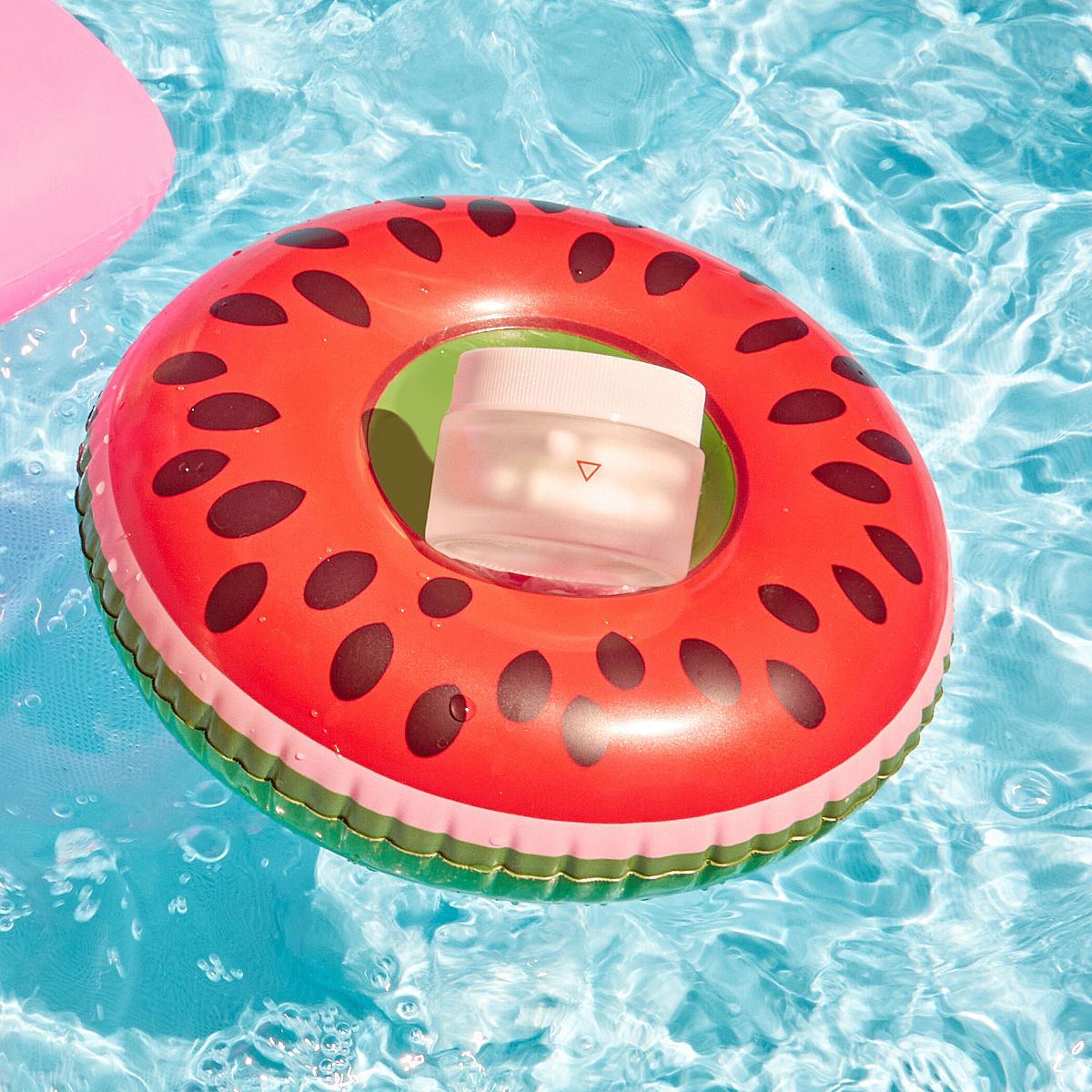 Small jar sitting in watermelon-esque pool ring on top of water