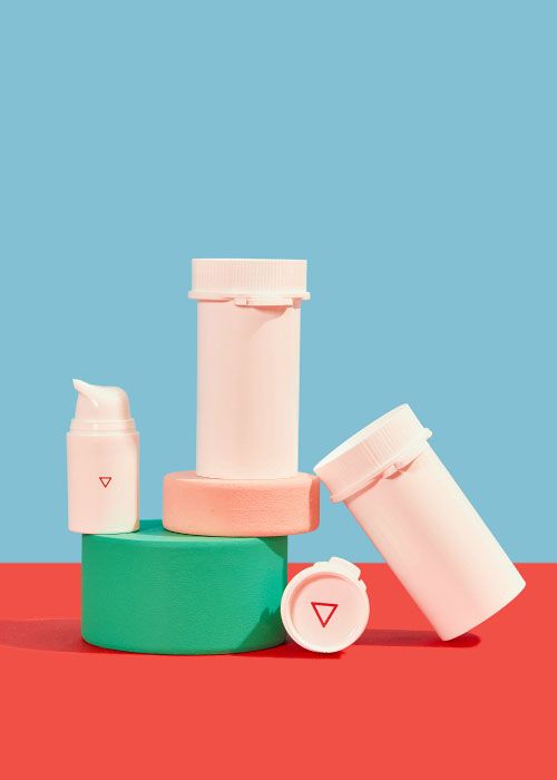 3 Wisp plastic vials and a pump bottle balanced on colorful abstract shapes on a red surface with a light blue background