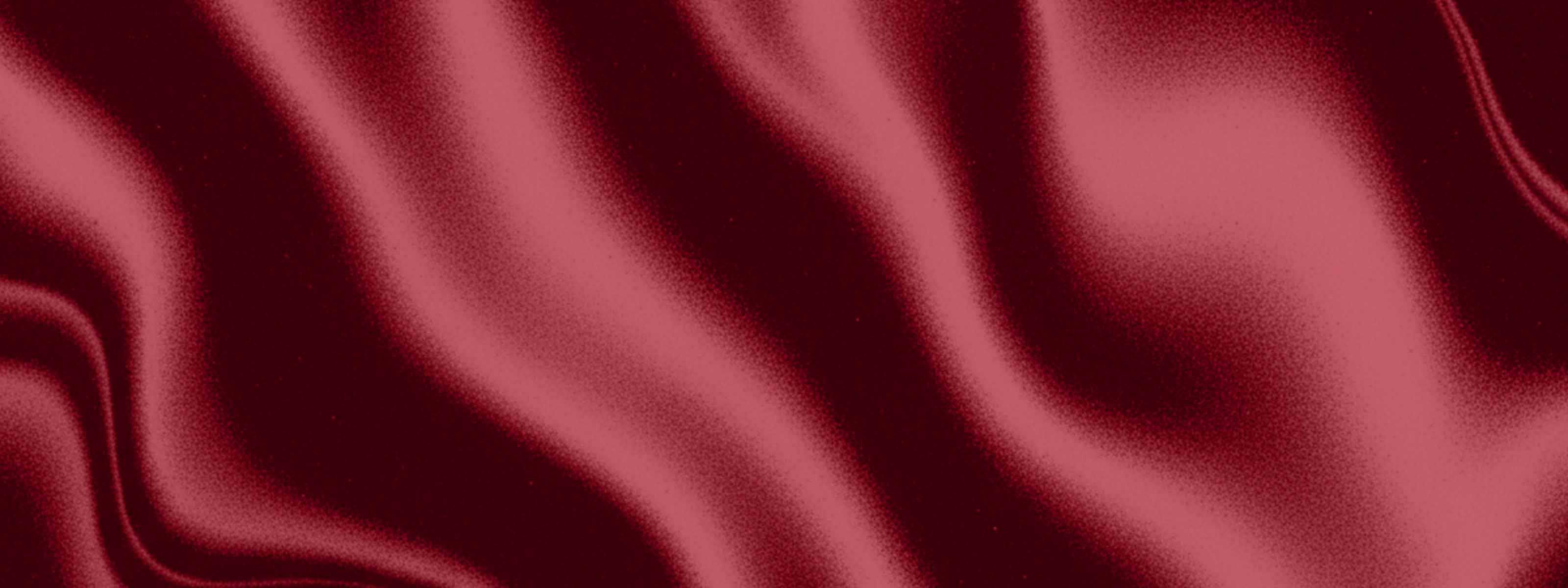 Flowing deep red satin fabric with soft folds and a silky sheen.