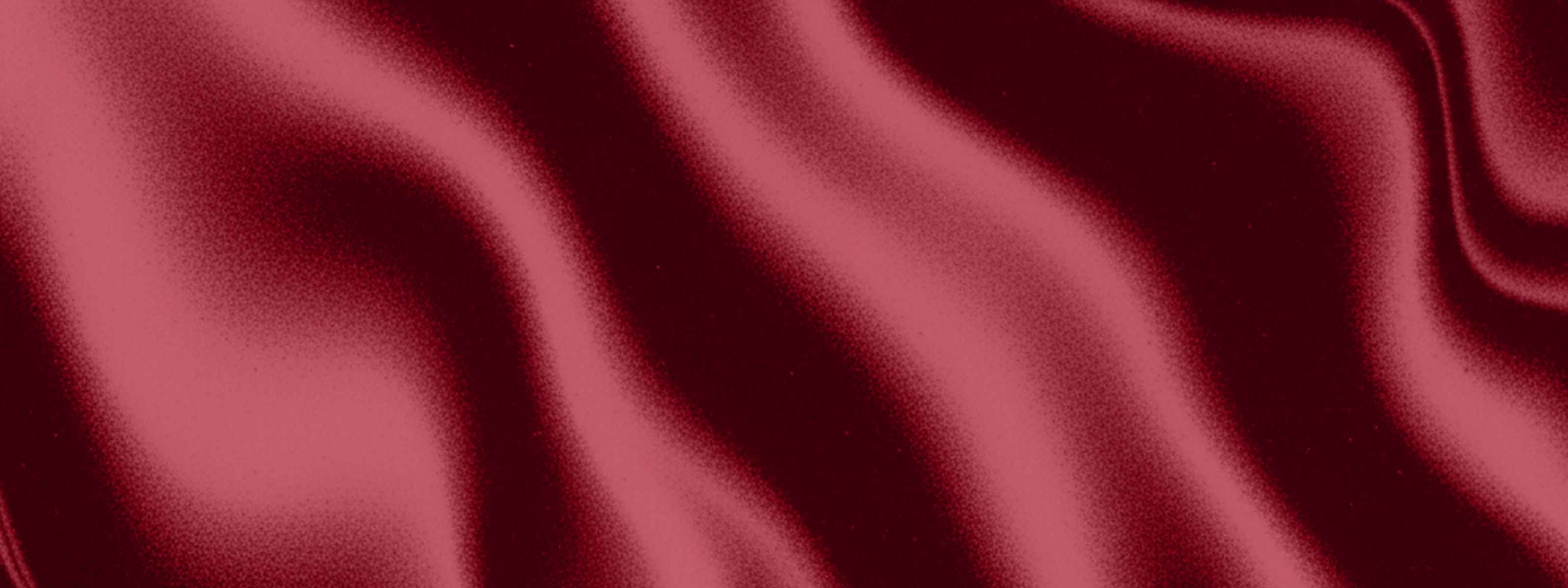 Flowing deep red satin fabric with soft folds and a silky sheen.