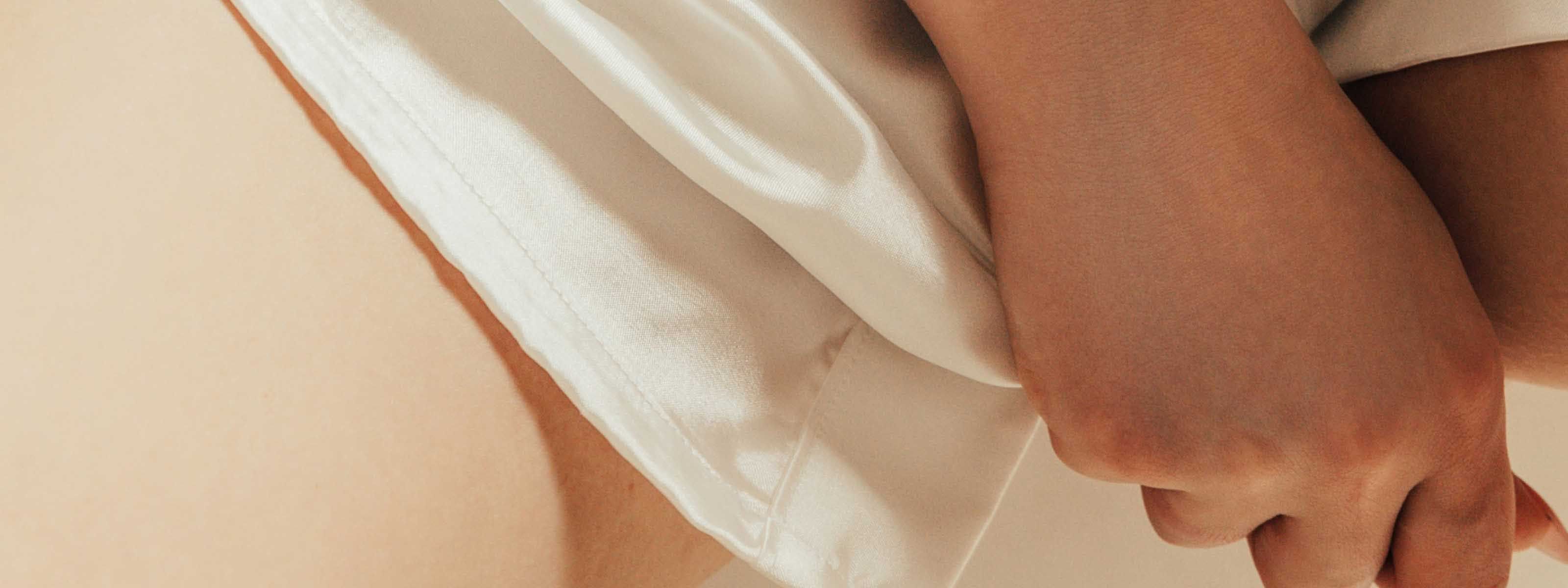 A close up of a hand adjusting the crotch of their white shorts