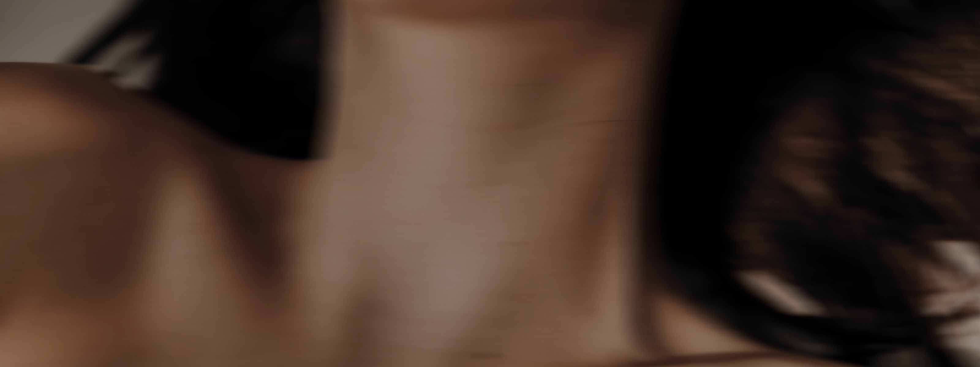 A close up of a woman's neck and collarbone with swept brunette hair.