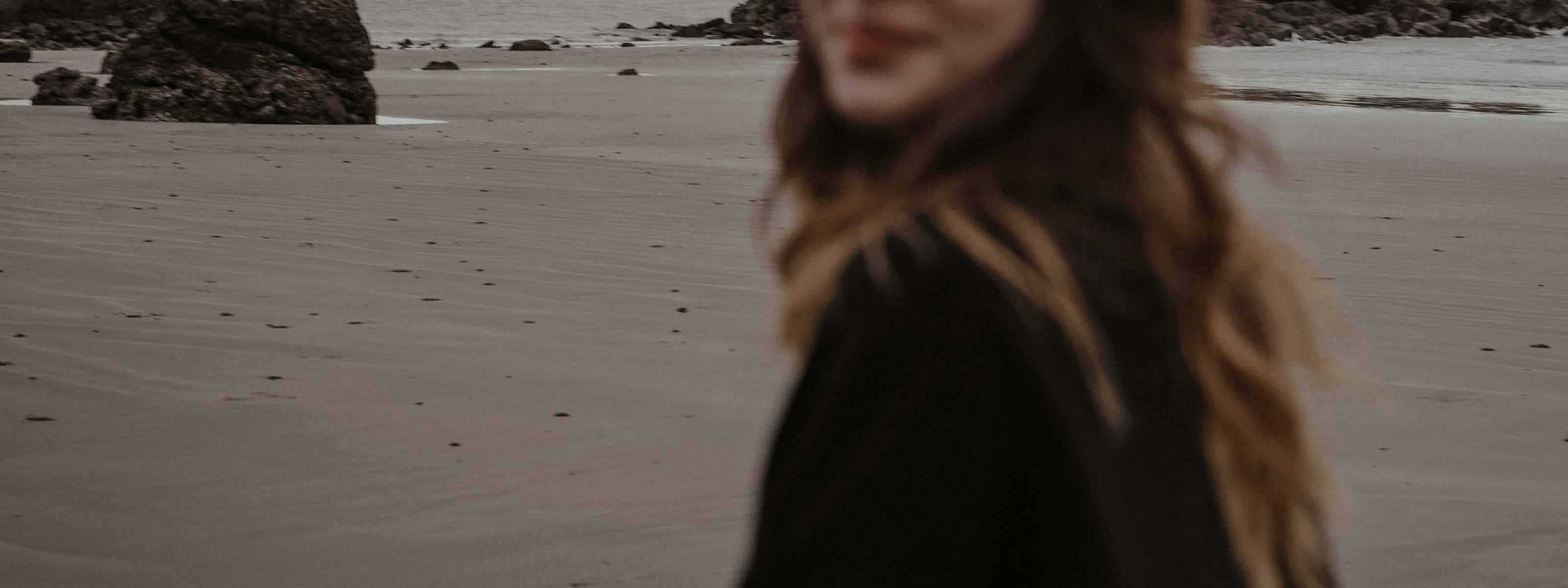Blurred figure standing on a beach with rocks in the background