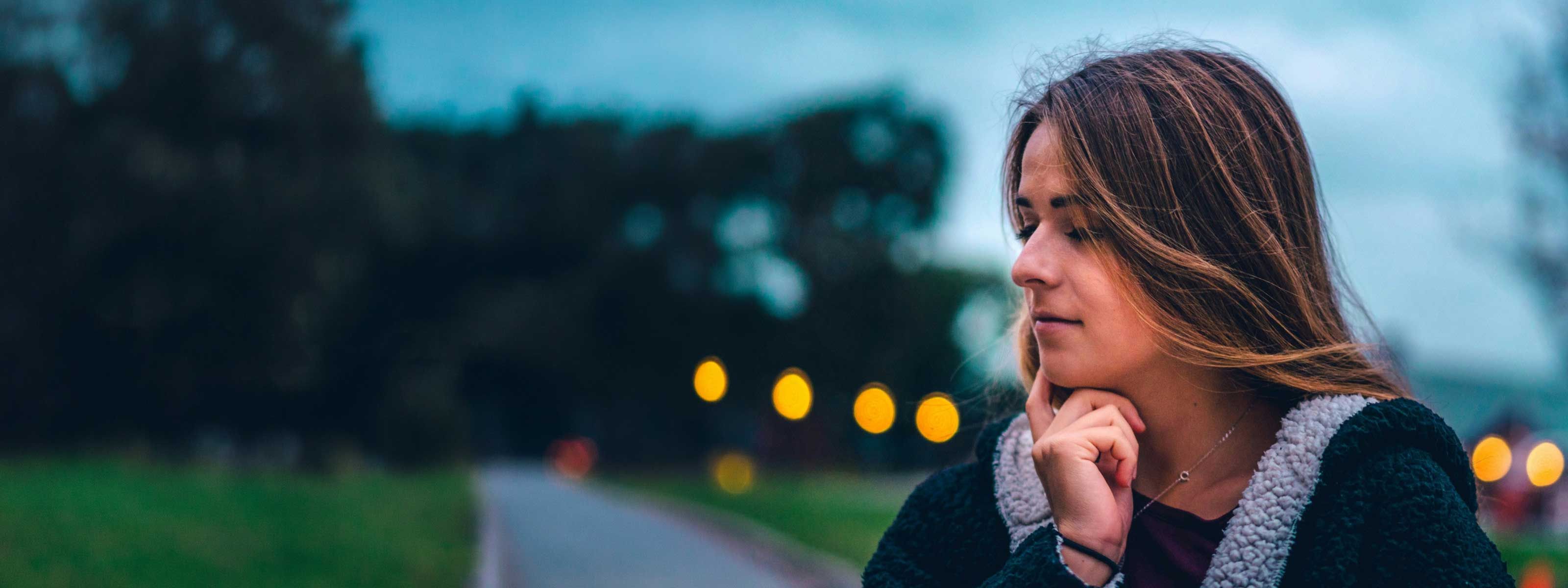 A woman looking contemplative while outside with stormy weather