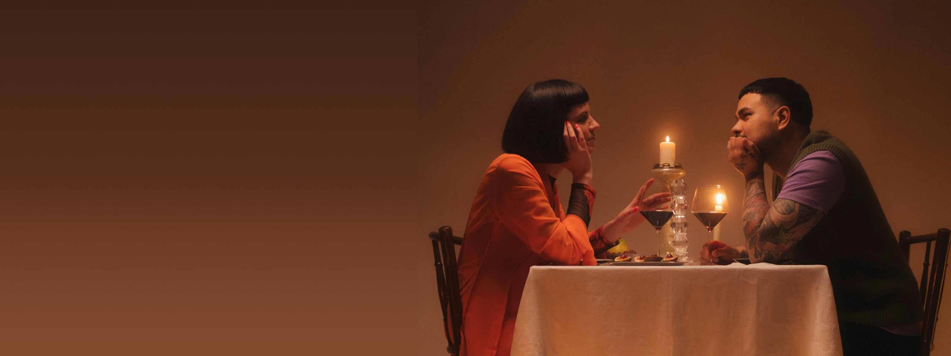 A coupld having and intimate candlelight dinner with wine
