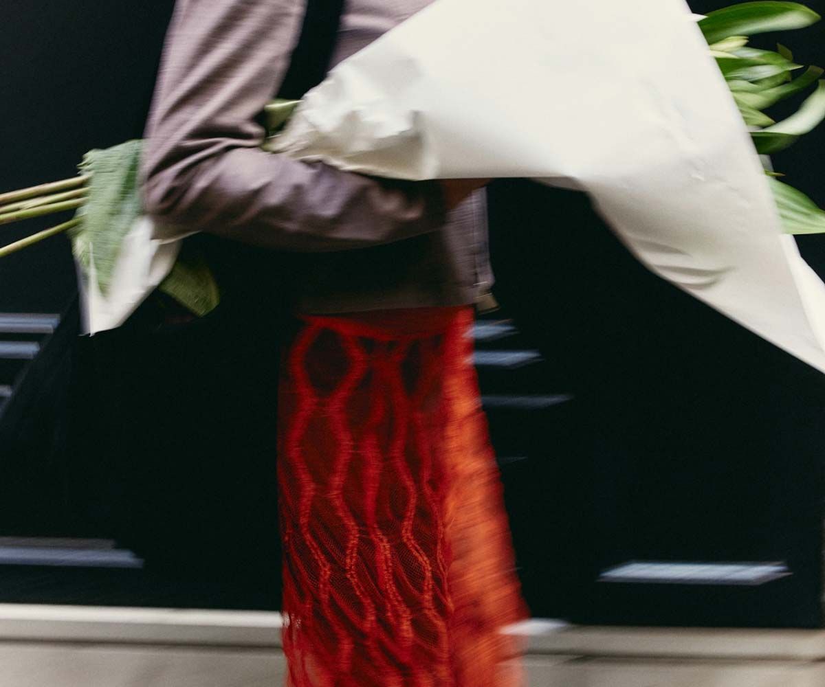 A woman wearing a red silk skirt while carrying flowers in the city