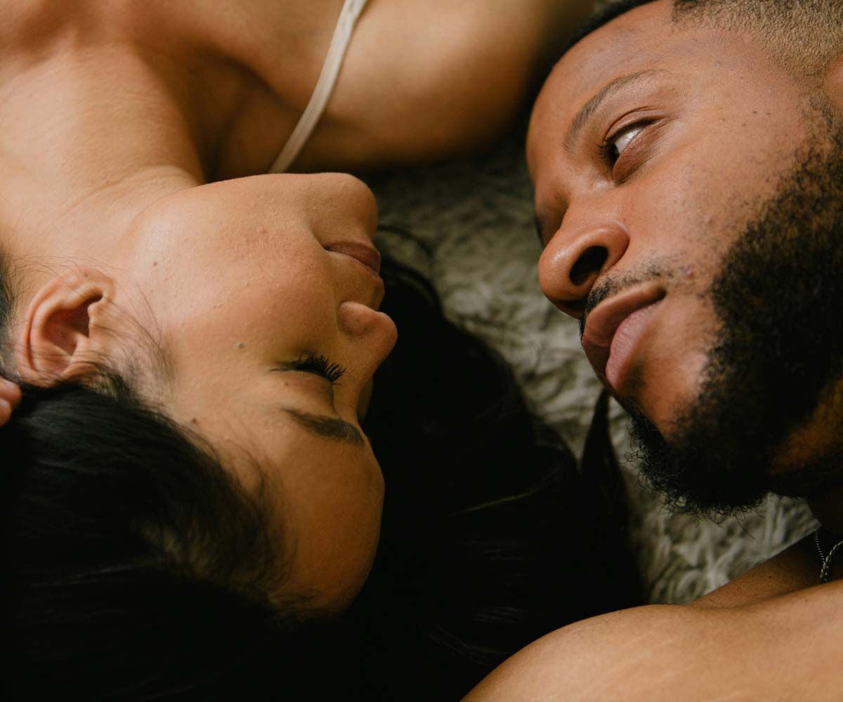 A woman and man laying next to each other with intimate expressions