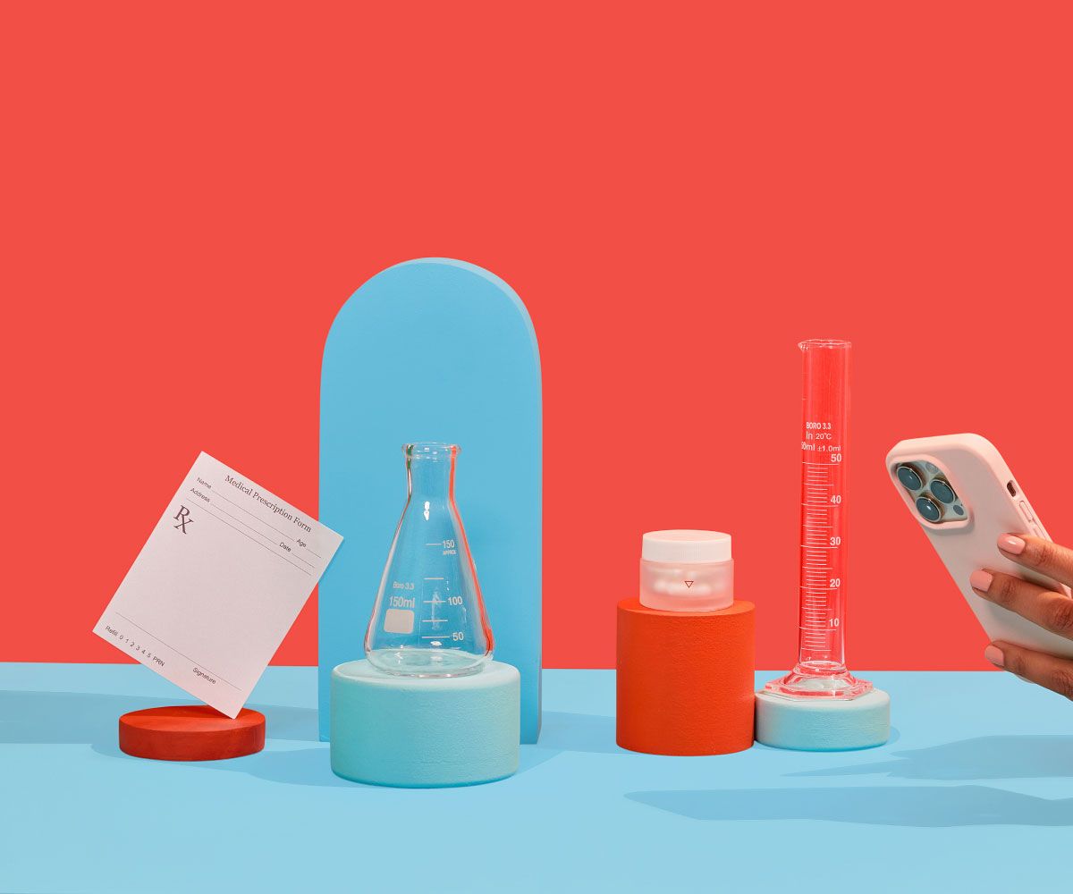 Wisp glass pill jar, test tubes, and a prescription script are balanced on colorful abstract shapes on a blue surface with a red background