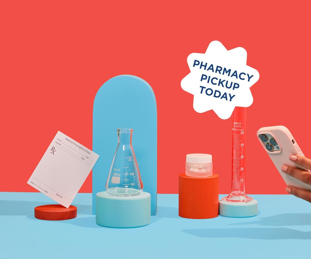 Wisp glass pill jar, test tubes, and a prescription script are balanced on colorful abstract shapes on a blue surface with a red background