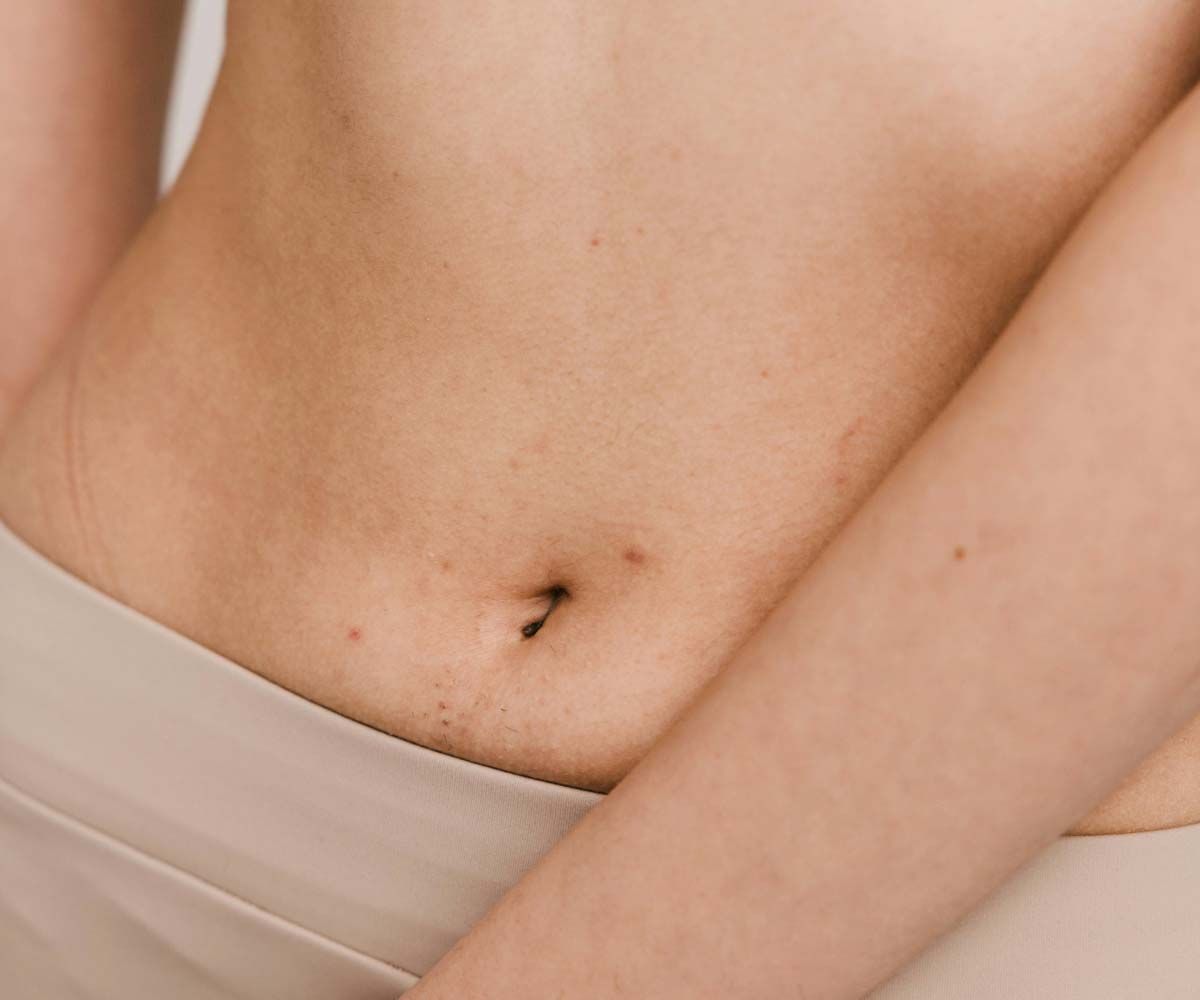 A close up of a woman's midsection with a cream background