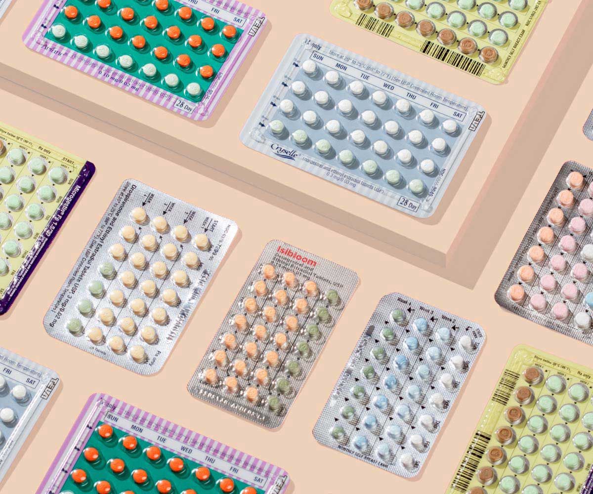 Various birth control pill packets on a cream background