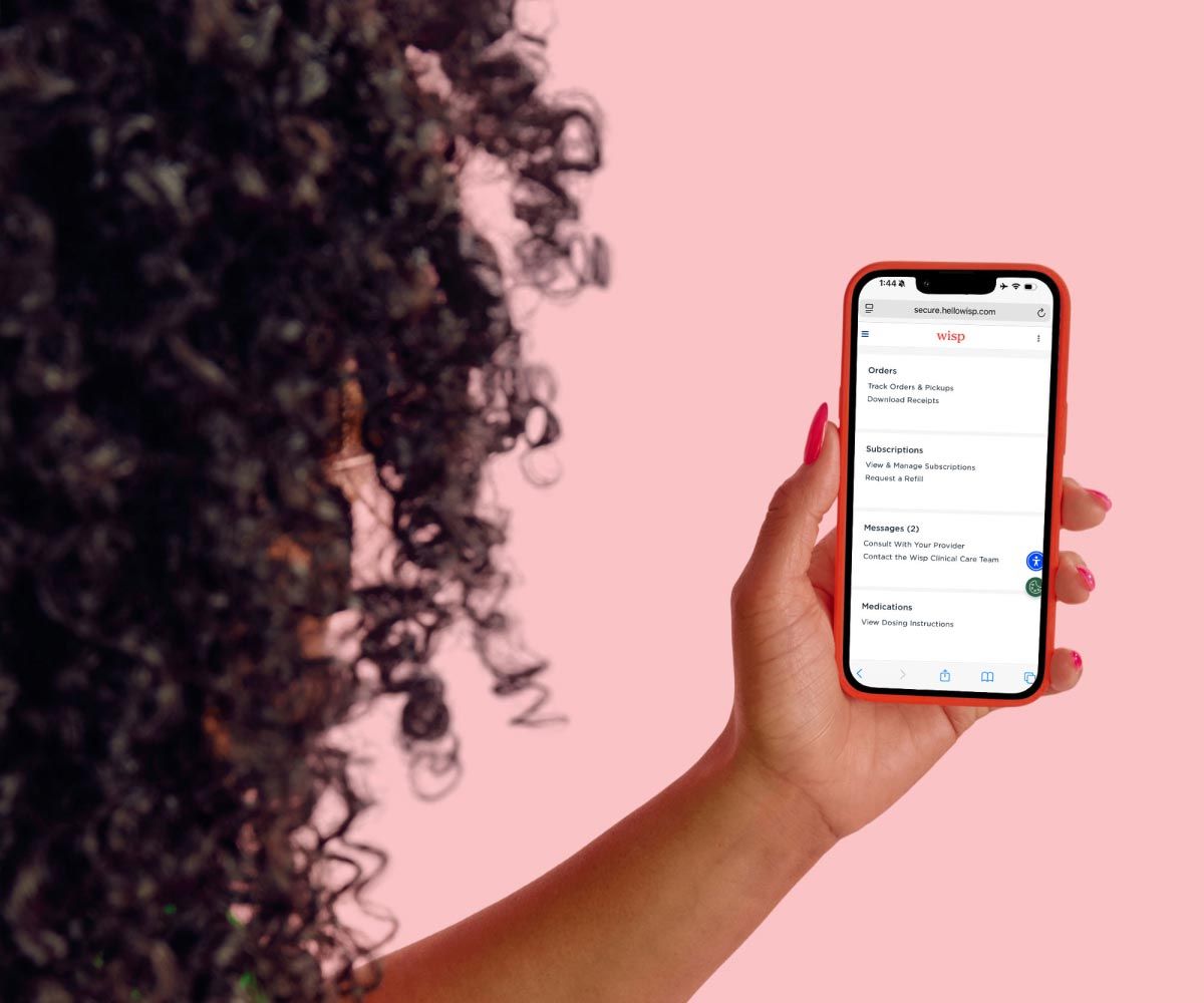 A woman holding a mobile phone with Wisp's account page on the screen