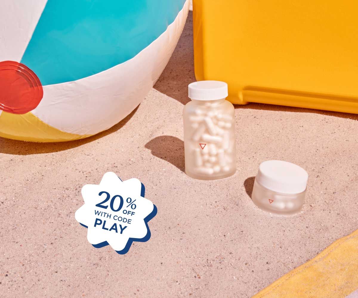 Wisp glass pill jars sitting on beach sand next to a beach ball