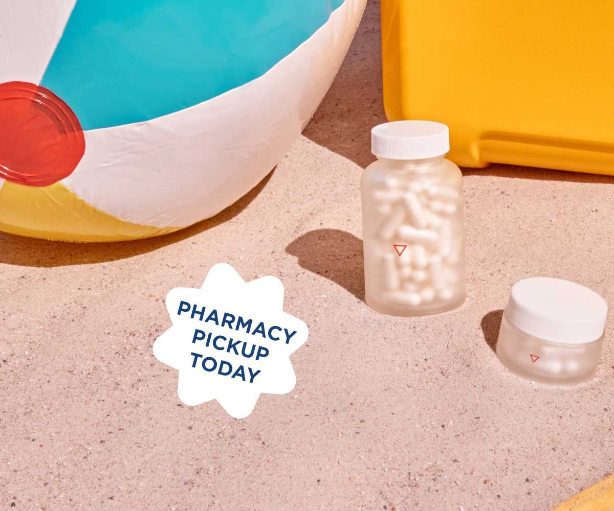 Two Wisp glass pill jars on beach sand next to a beach ball and chair