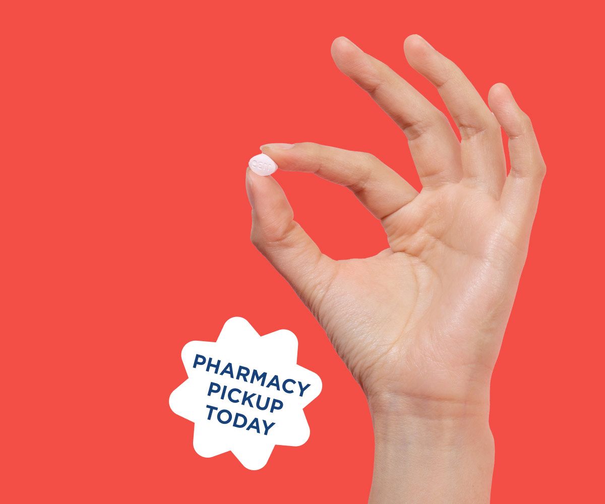 Hand holding fluconazole pill for same-day yeast infection treatment on a red background