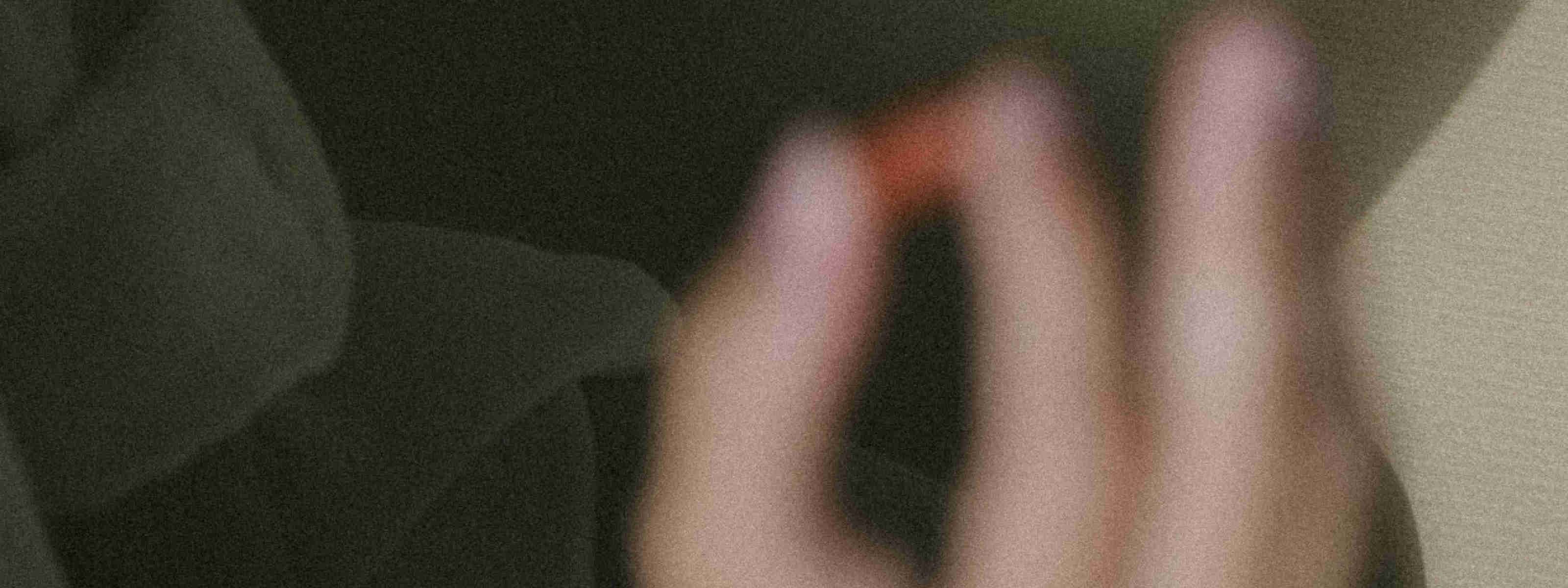 a blurry image of a hand holding a pill in front of a dark background
