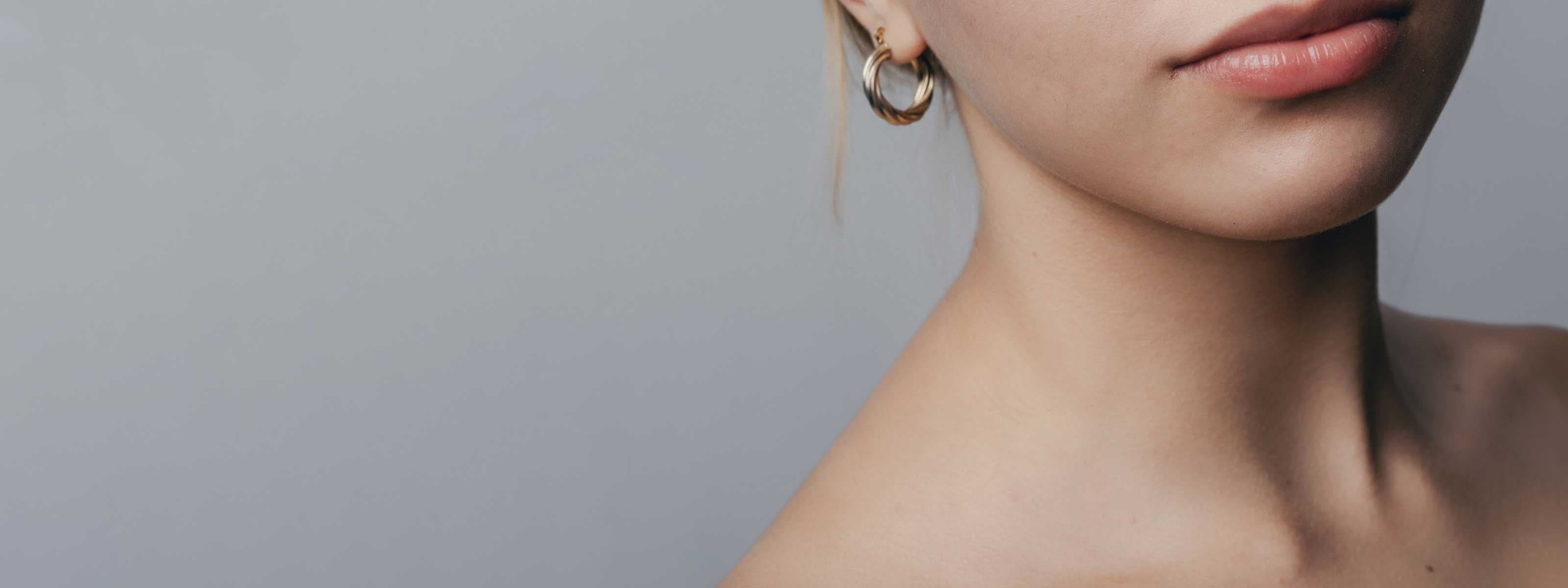 A close up of a woman's neck with a gray background