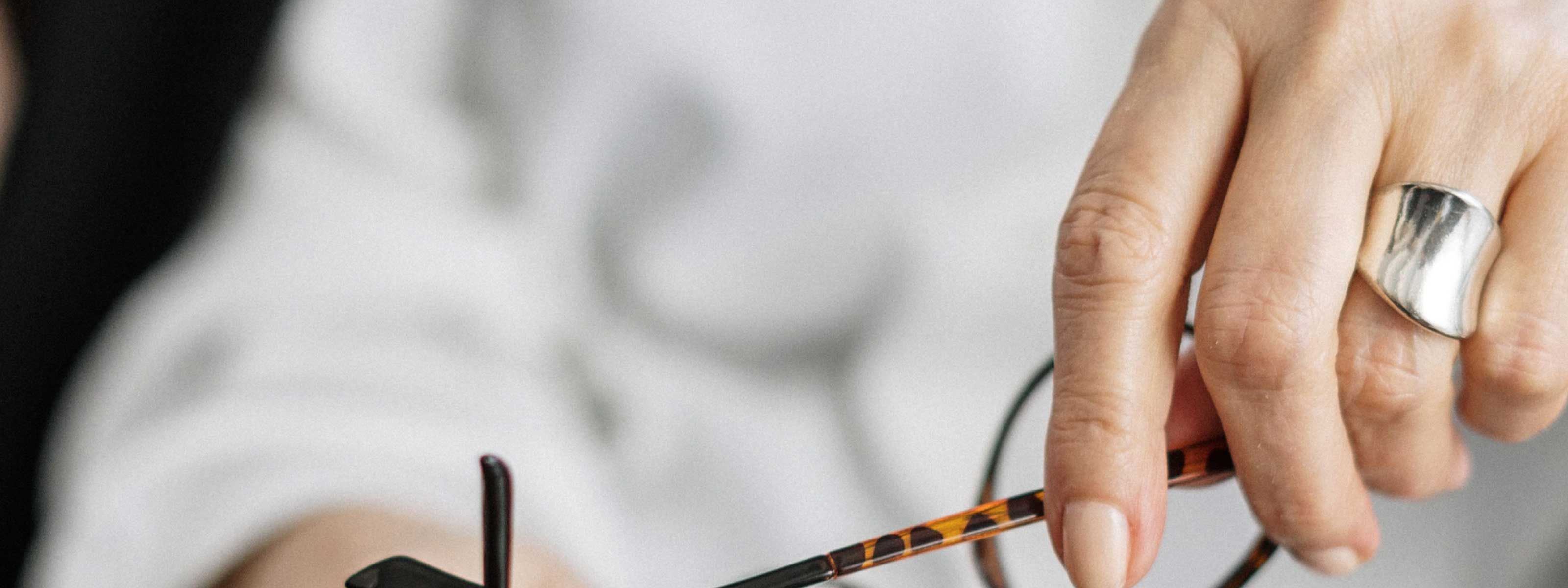 A woman wearing a white button up shirt is holding her glasses with a strained look on her face
