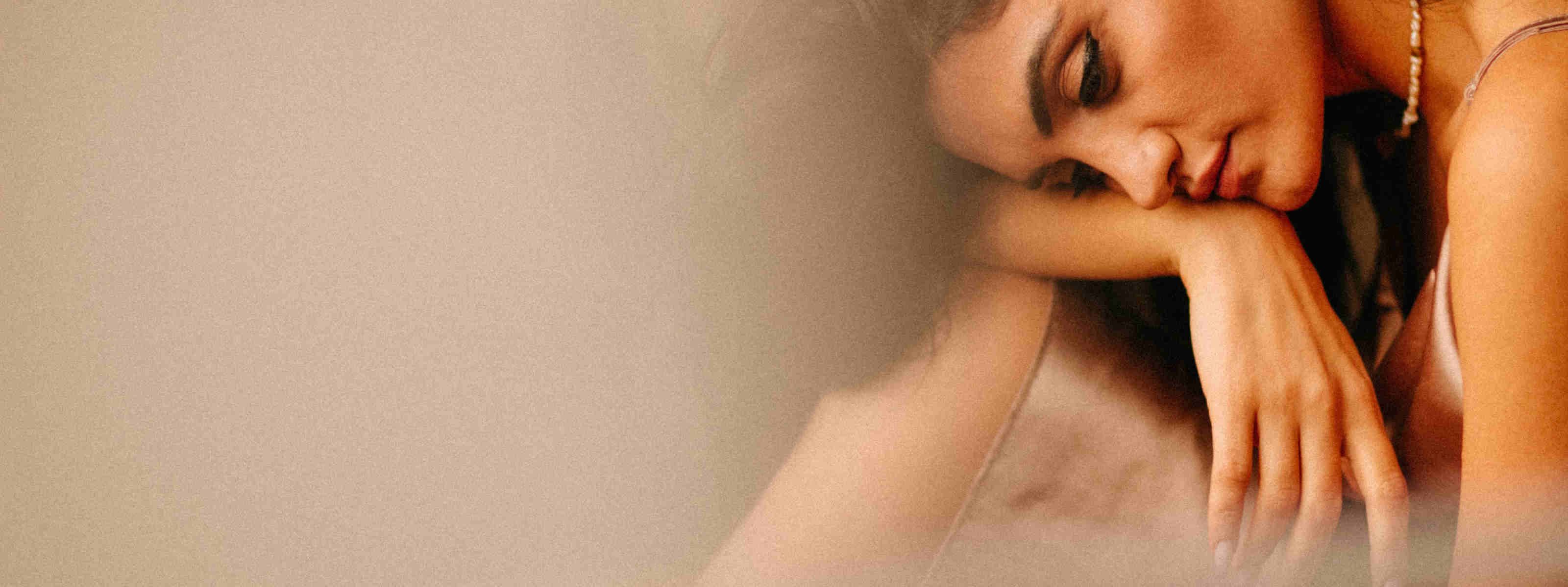 Tired woman leaning her head on her arm, representing menopause-related fatigue.