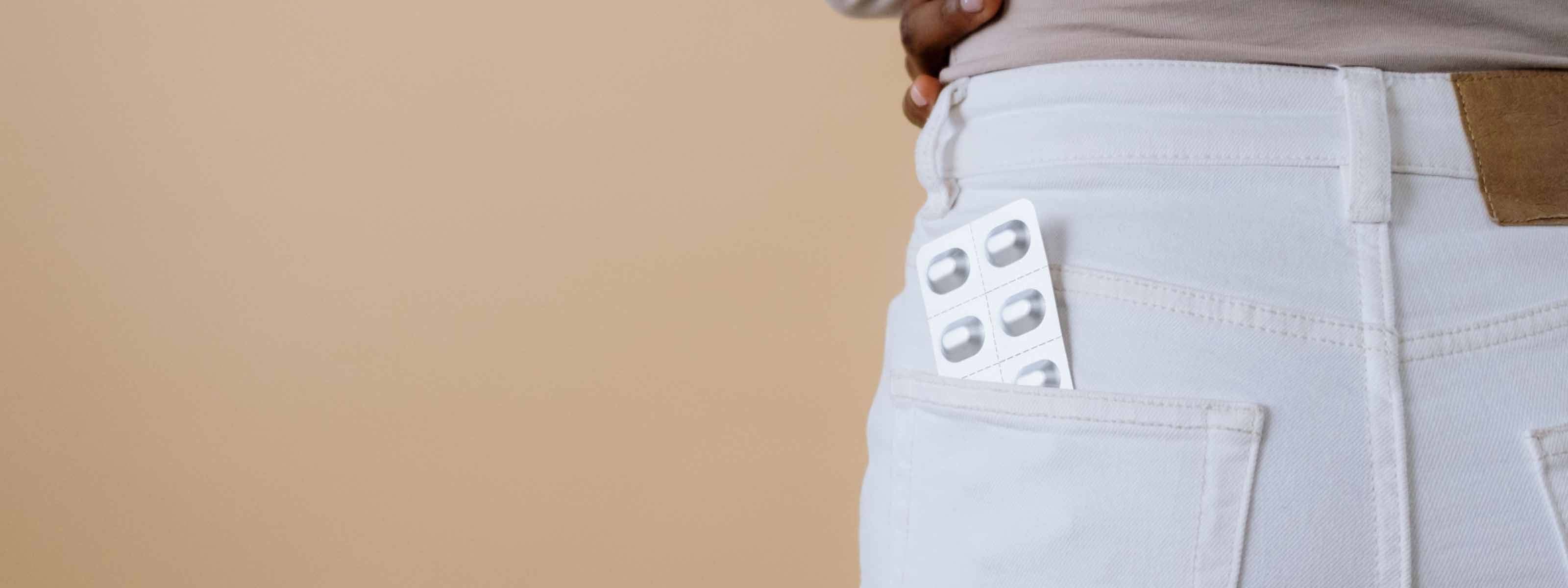 A woman wearing white jeans with a pill packet in her back pocket
