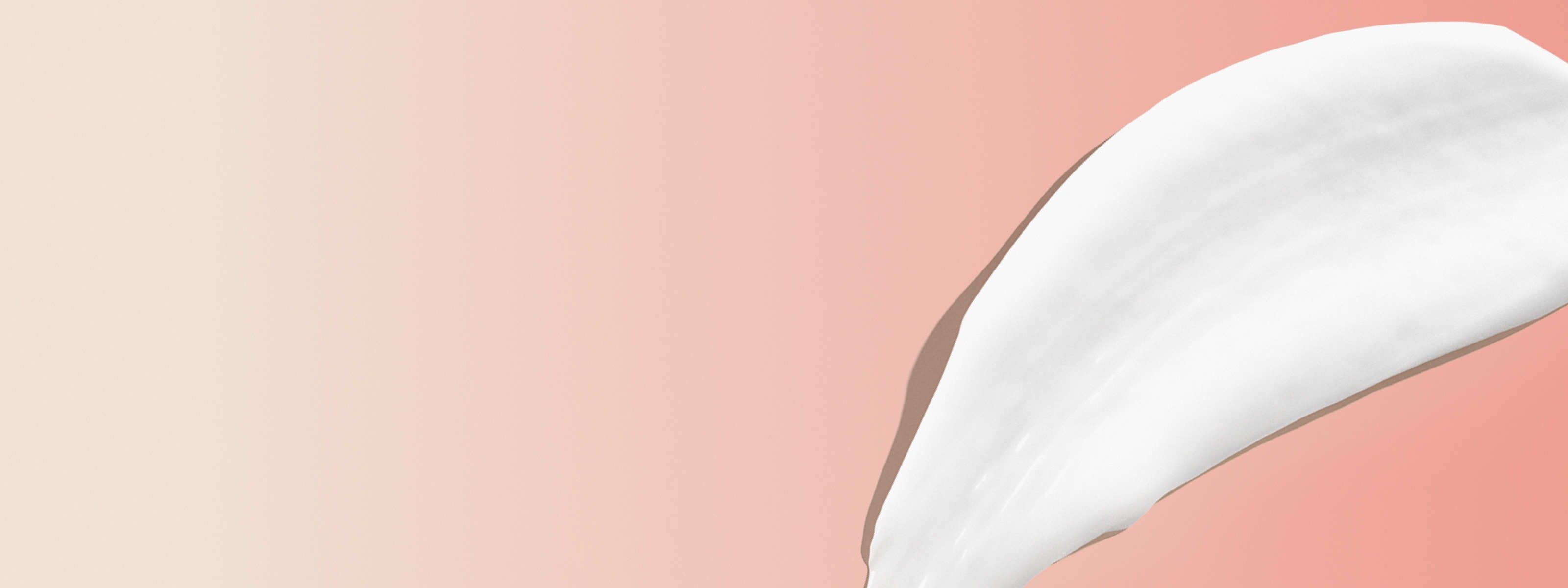 swipe of white clindamycin cream in front of a light orange and beige background