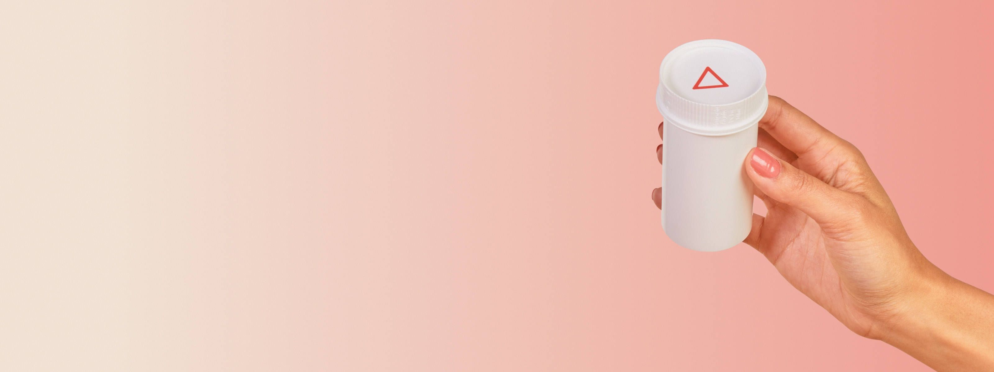hand holding a white wisp pill bottle in front of a red and beige background