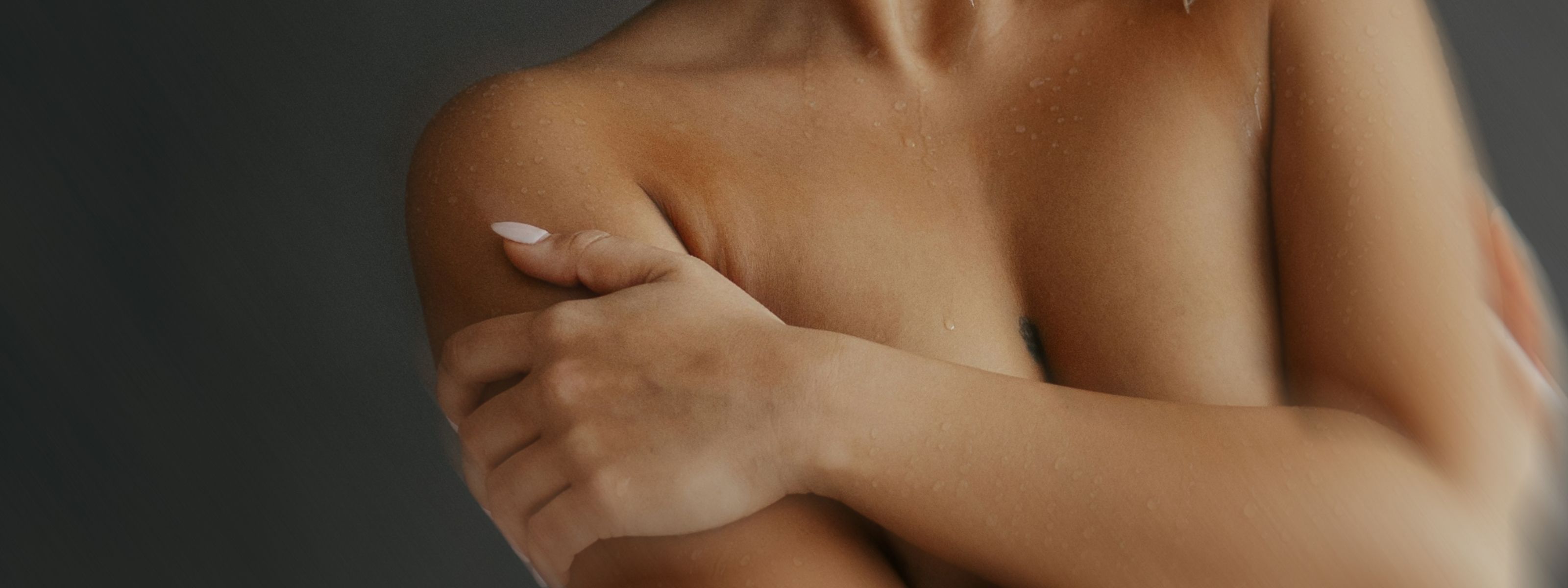 image of a persons chest and torso holding arms in front of a gray background