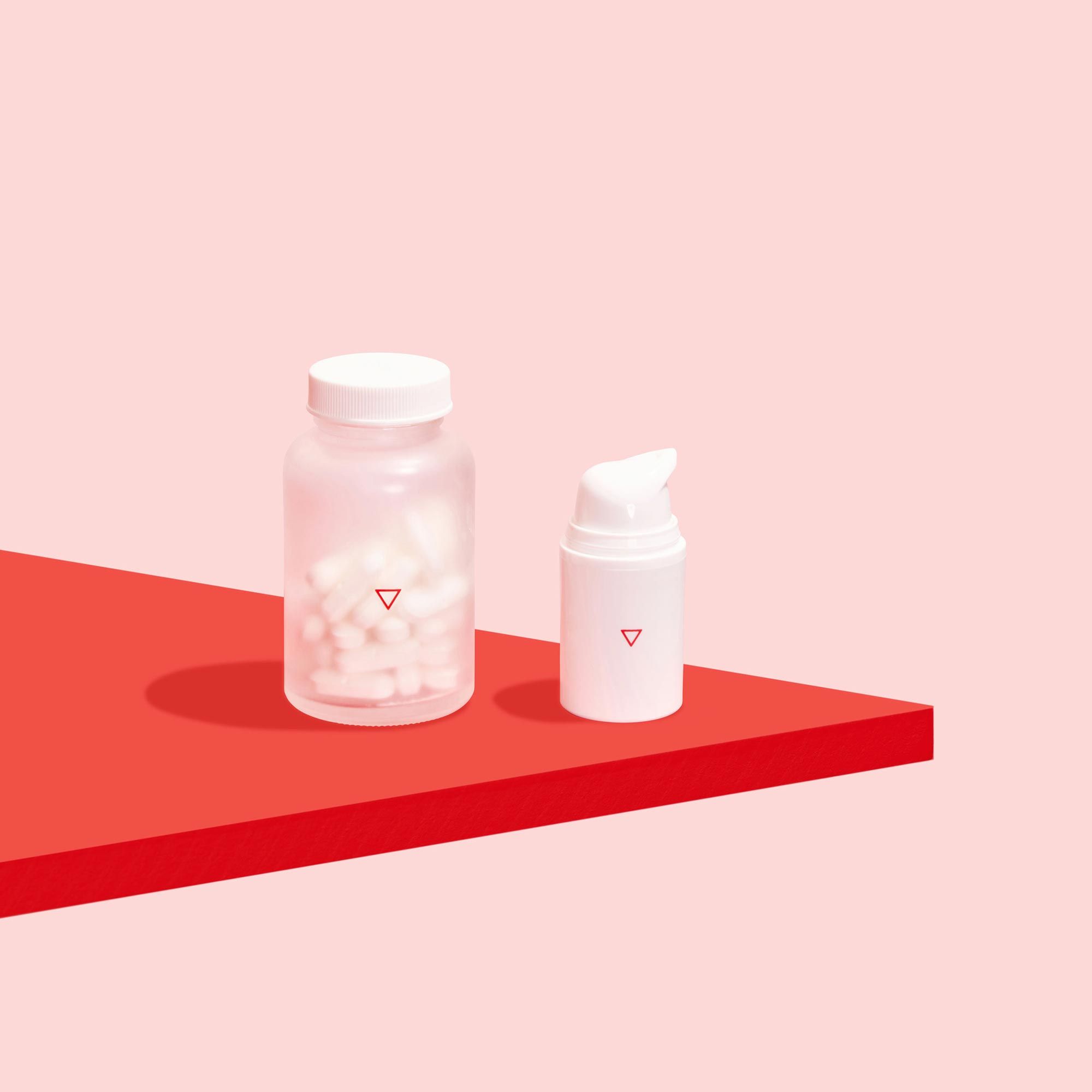 Jar of oral acyclovir pills and bottle of topical acyclovir cream to treat herpes outbreaks on red surface, on pink background