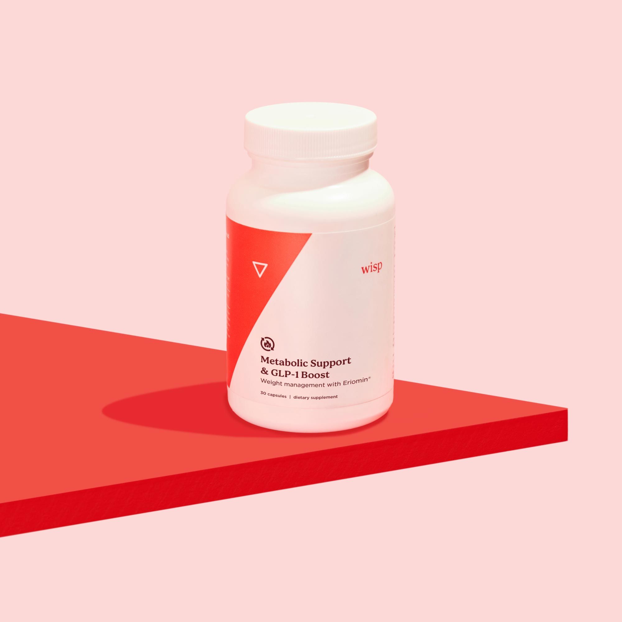 A plastic Wisp pill vial on a red surface with a pink background