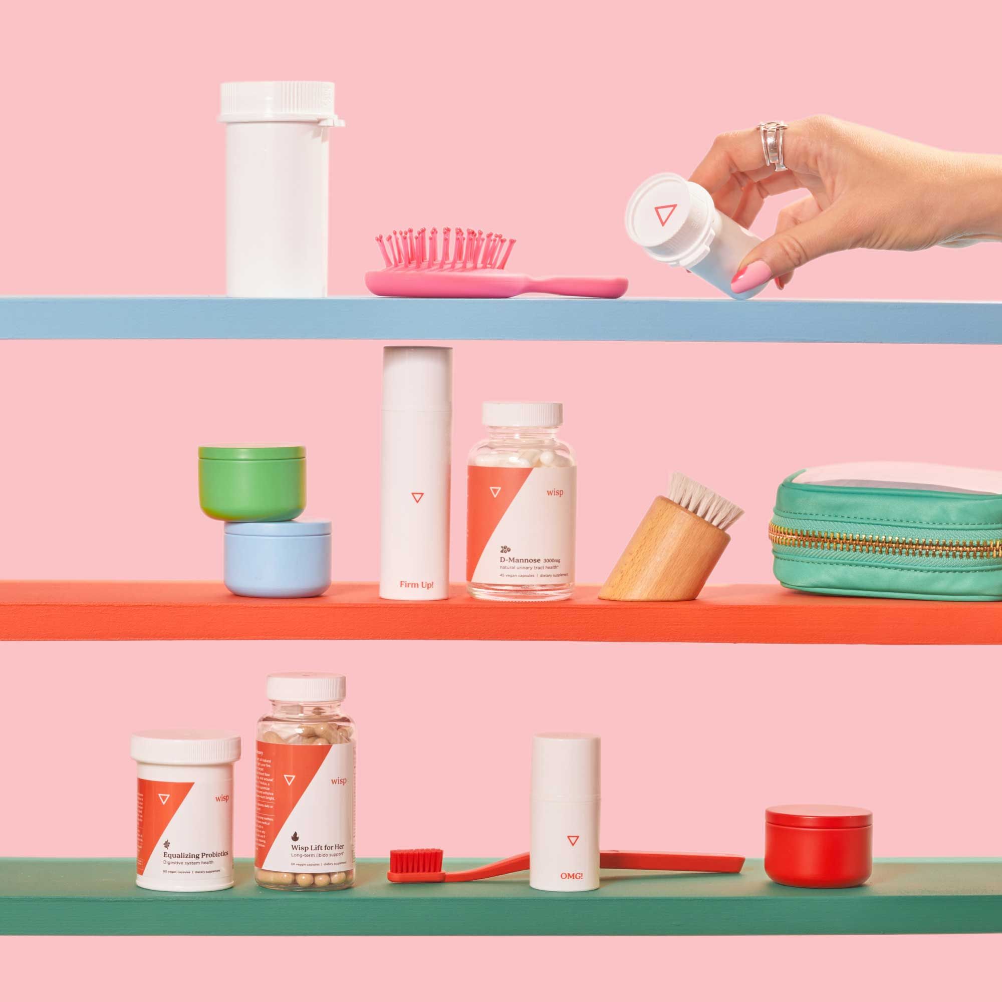 A woman's hand reaching for a Wisp medication bottle on colorful shelves with various Wisp medication bottles in front of a pink background