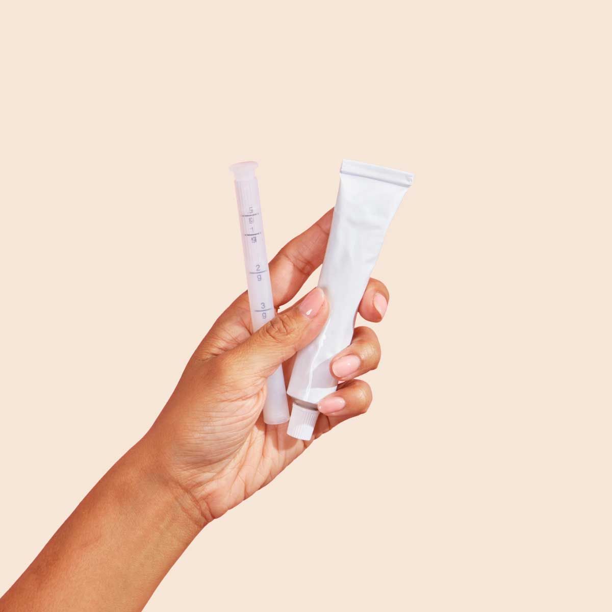 Tube of estradiol cream and applicator on a cream backround