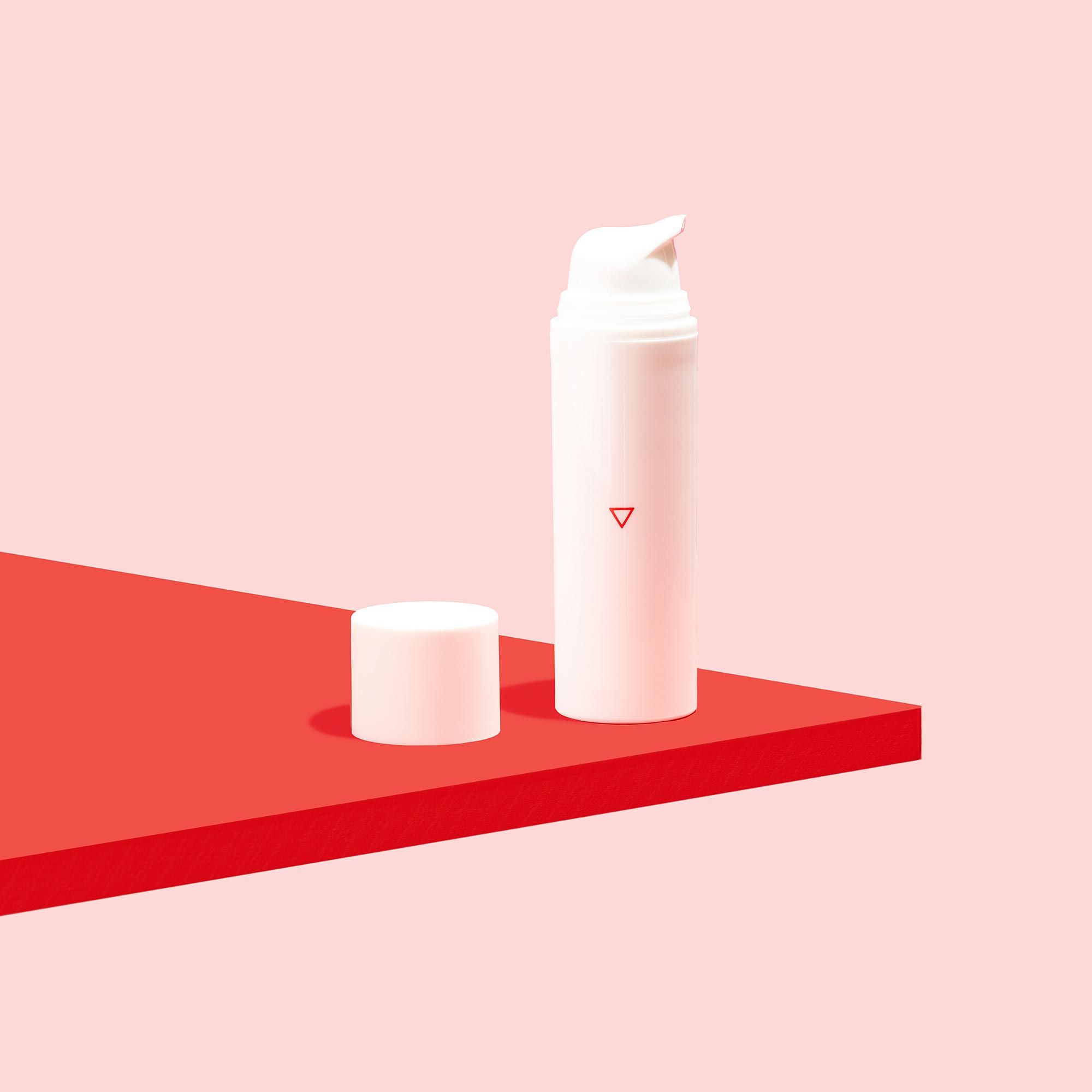A Wisp pump bottle on a red surface with a pink background