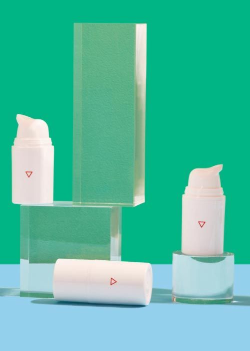 3 Wisp pump bottles balanced on clear abstract shapes on a light blue surface with a green background