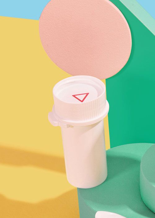 A Wisp plastic pill vial balanced on colorful abstract shapes on a yellow surface