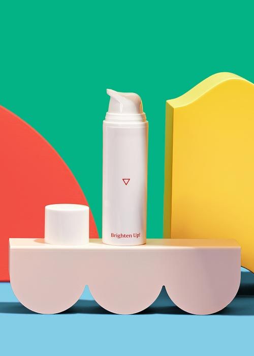 Wisp Brighten Up! Hydroquinone Cream bottle balanced on colorful abstract shapes on a light blue surface with a green background