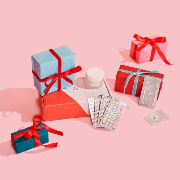 Birth control and emergency contraception packets with colorful gift wrapped boxes on a pink surface