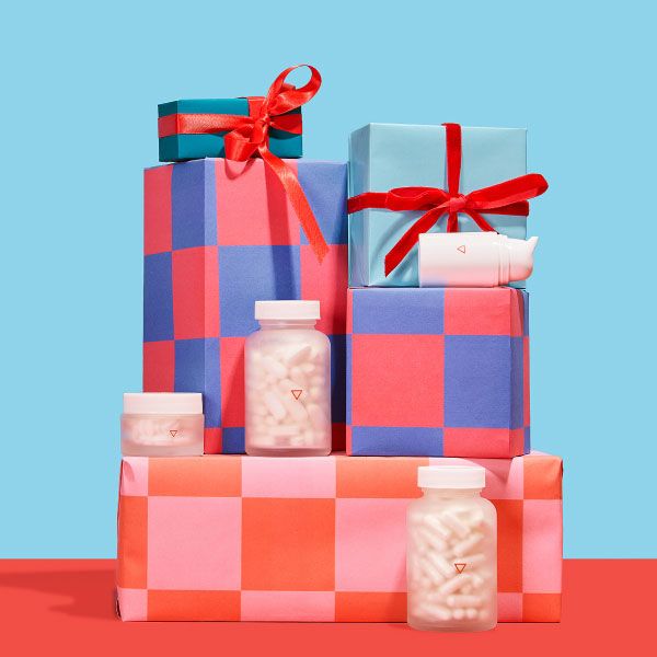 Various Wisp products balanced on colorful gift wrapped boxes on a red surface with a light blue background