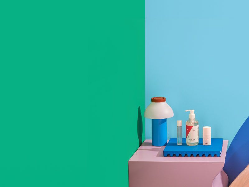 Wisp's Better Sex products on a nightstand with a lamp, colorful abstract shapes and a blue and green background